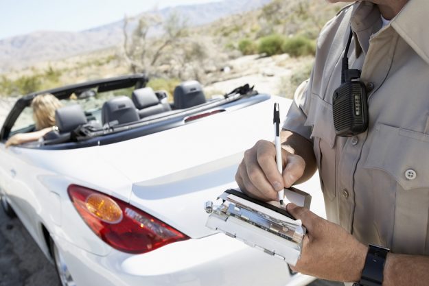 Closeup of a cropped police officer writing traffic ticket to wo